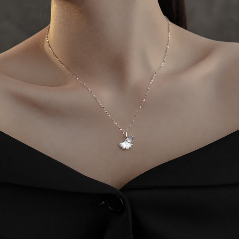 Supplier model wearing the silver and white ginkgo leaf necklace with a black neckline