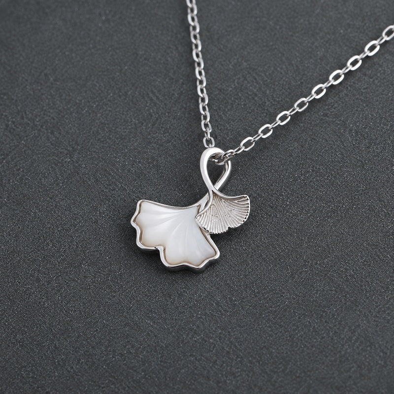 Oblique view of the ginkgo pendant resting on a textured charcoal surface
