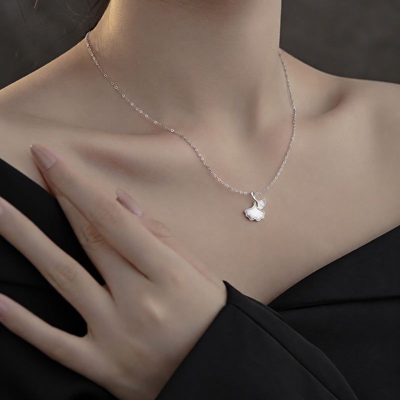 Supplier model wearing the ginkgo necklace with her hand near the shoulder