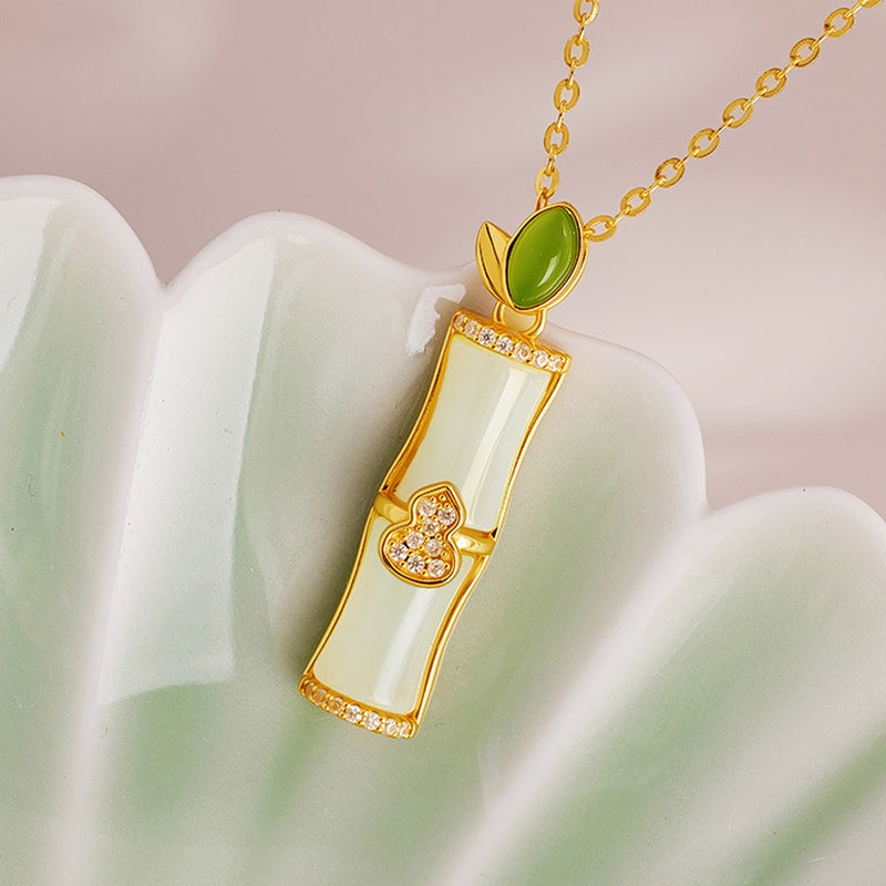 Jade bamboo gourd necklace on a pale green ceramic prop