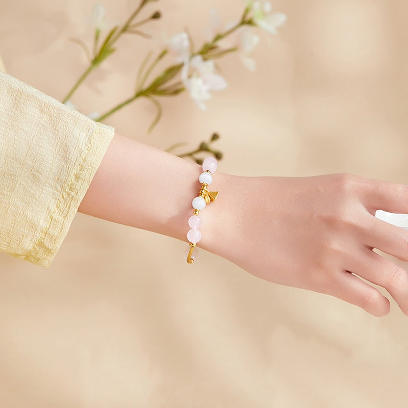 Rose quartz lotus bracelet worn with a cream sleeve