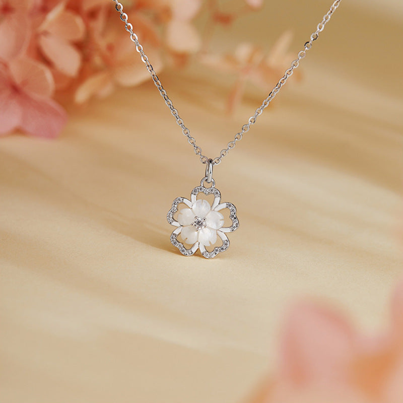 Mother-of-pearl cherry blossom necklace on a warm floral background