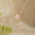 Peach blossom silver tassel necklace against a warm blurred background