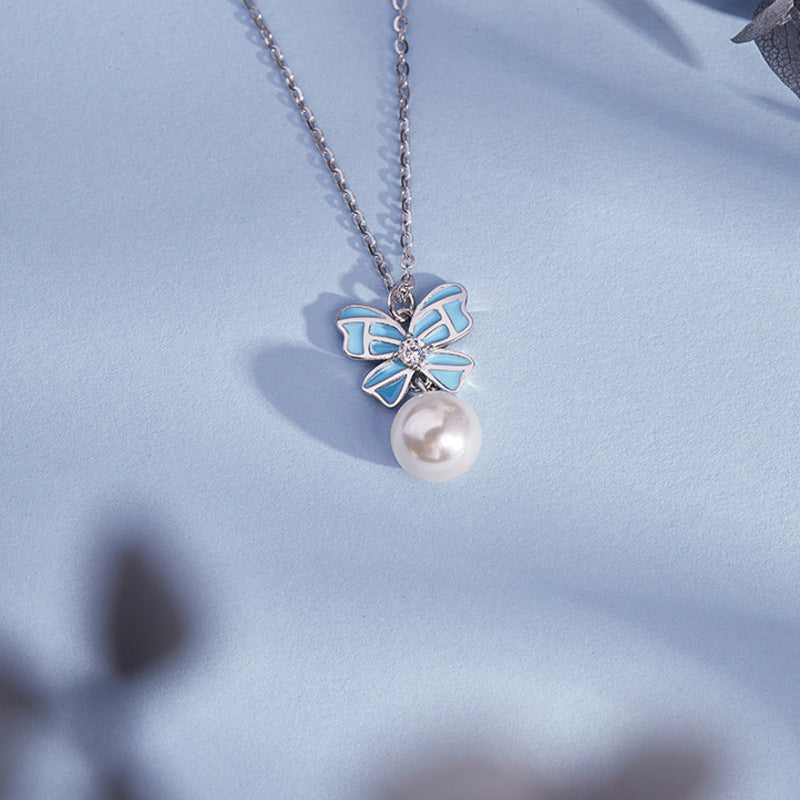 Blue bow necklace resting on a blue surface
