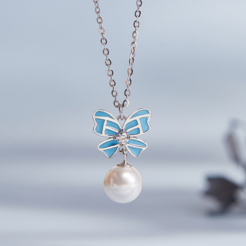 Close front view of the blue luminous enamel bow and imitation pearl