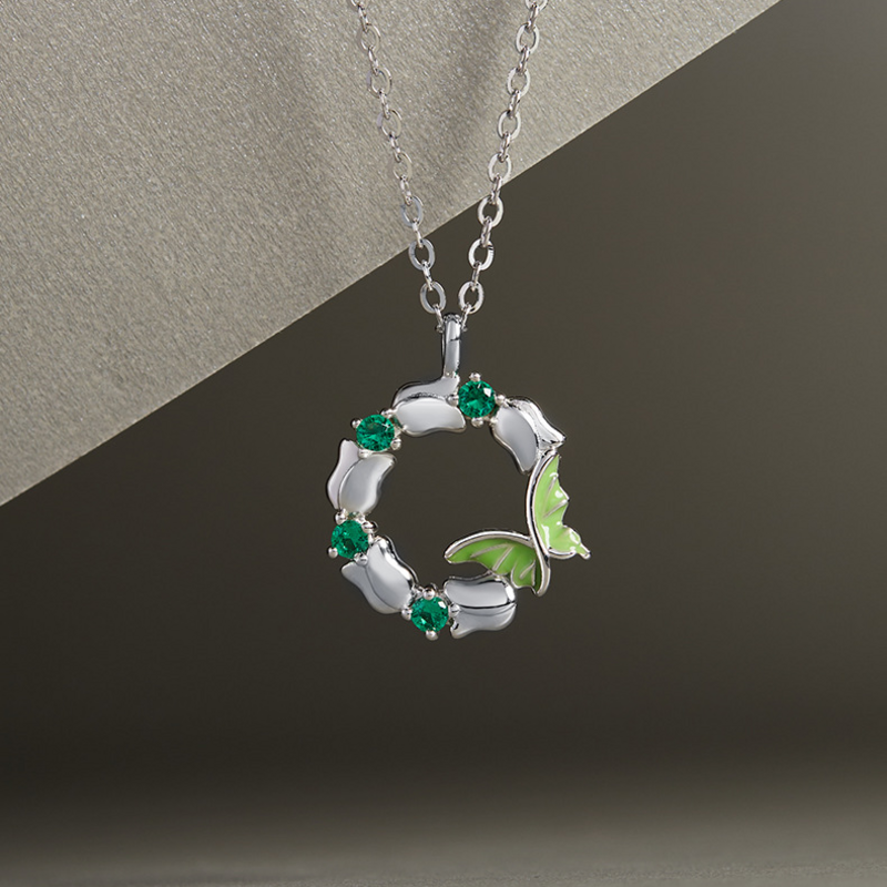 Green enamel butterfly wreath silver necklace against the original textured silver and dark background