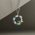 Green enamel butterfly wreath silver necklace against the original textured silver and dark background