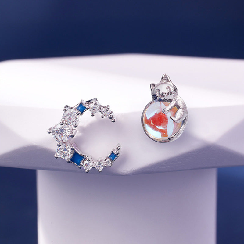 Cat and moon silver stud earrings on a blue and white display
