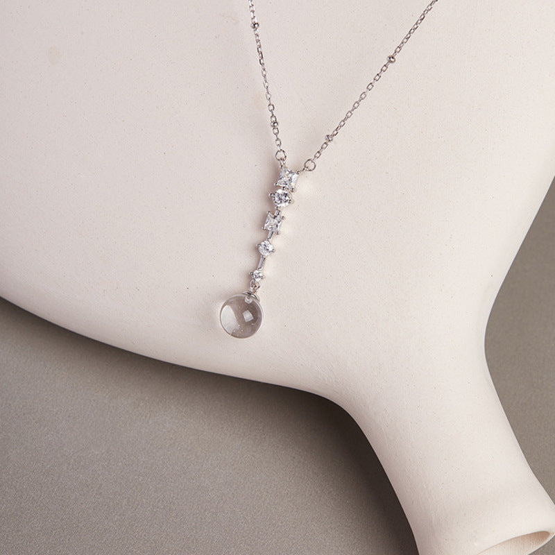Clear quartz pendant resting on sculptural cream ceramic