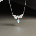 Dragonfly silver necklace with iridescent glass drop against a dark background