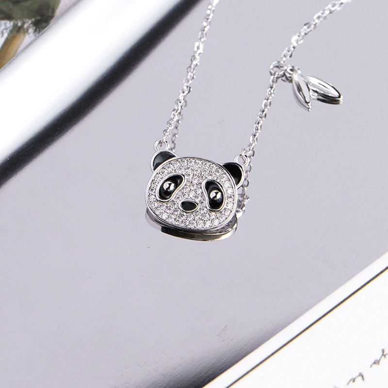 Panda silver necklace resting on a reflective pale background