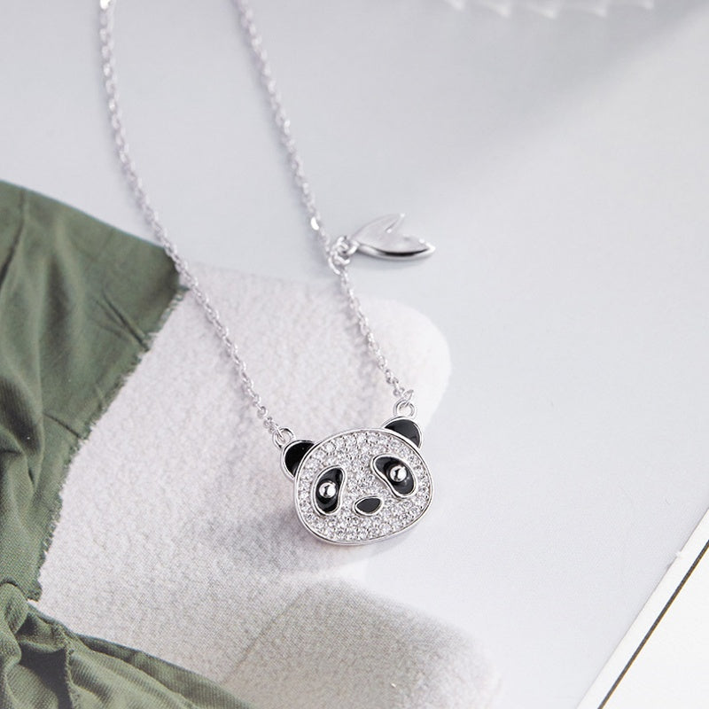 Panda pendant on pale fabric beside a green leaf