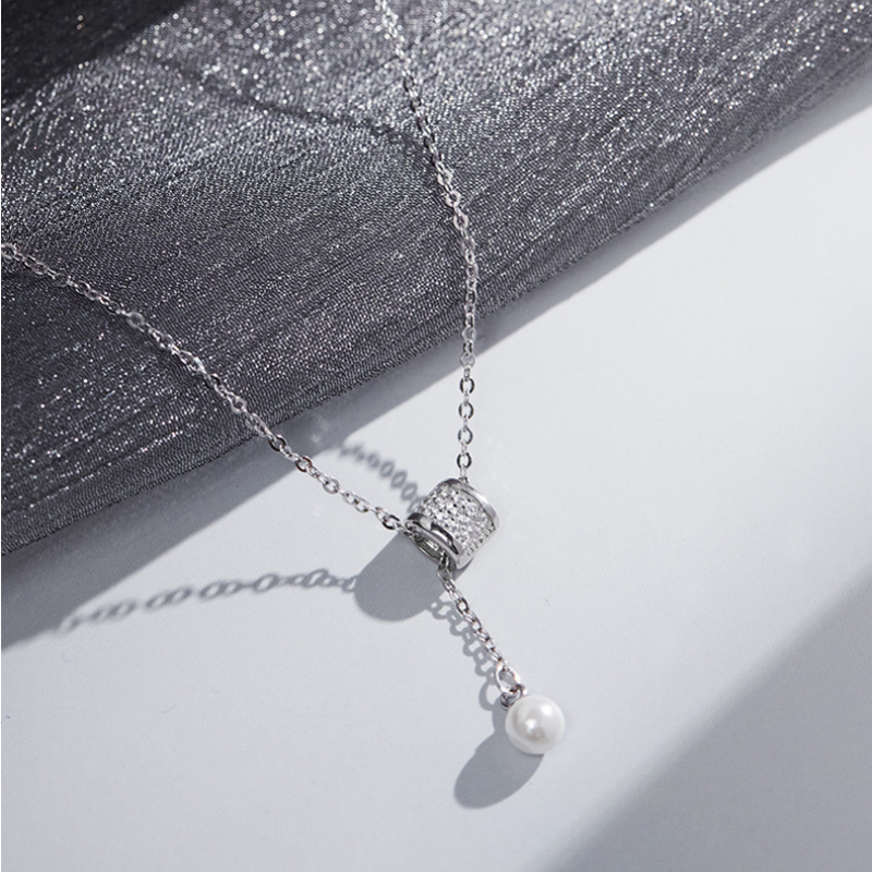 Silver necklace with imitation pearl drop on a textured silver background