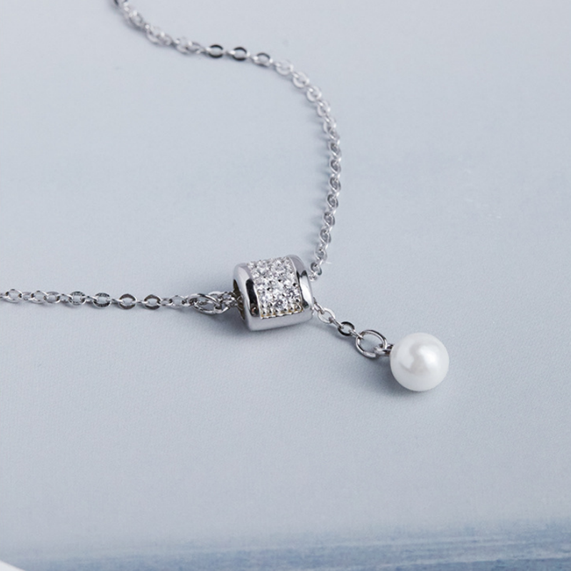 Oblique close-up of the silver pendant and imitation pearl