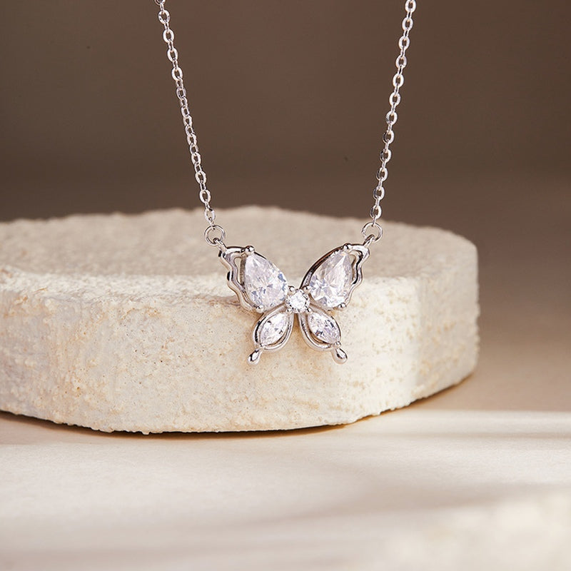 Photochromic cubic zirconia butterfly silver necklace on a cream stone display