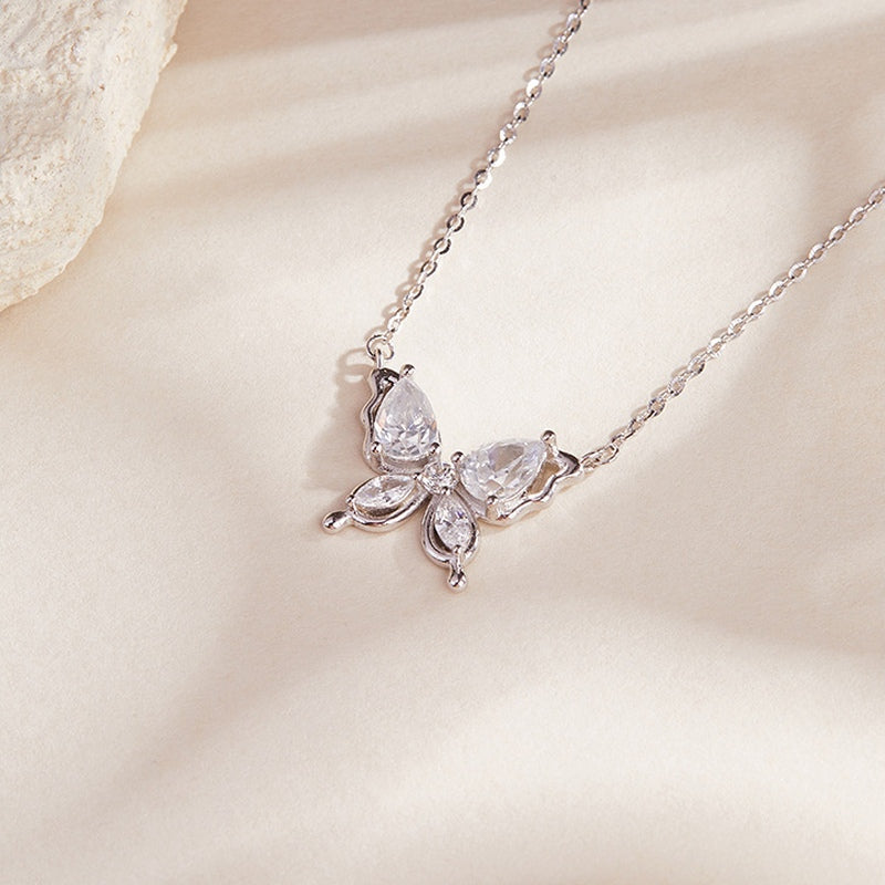 Butterfly necklace resting on softly lit cream fabric