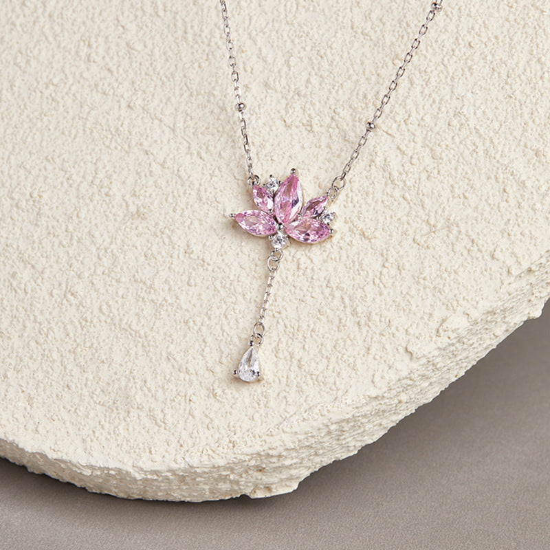 Pink lotus silver tassel necklace on a textured cream display