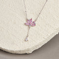 Pink lotus silver tassel necklace on a textured cream display