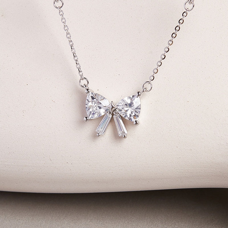Silver bow necklace against a pale textured display
