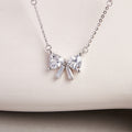 Silver bow necklace against a pale textured display