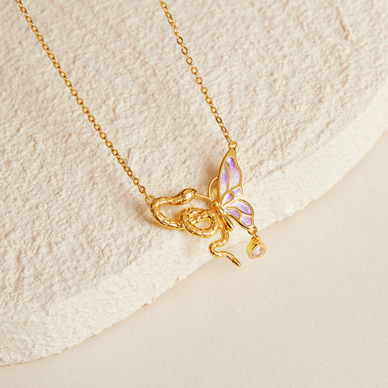 Snake butterfly necklace resting on cream textured stone