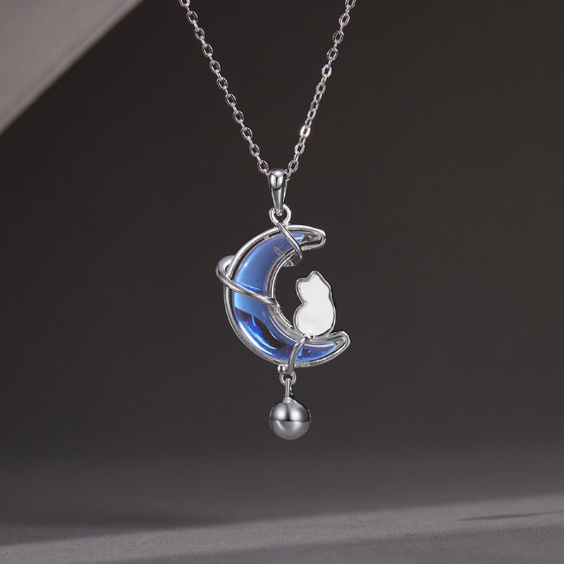 Cat and iridescent moon necklace with hanging bell against a gray background