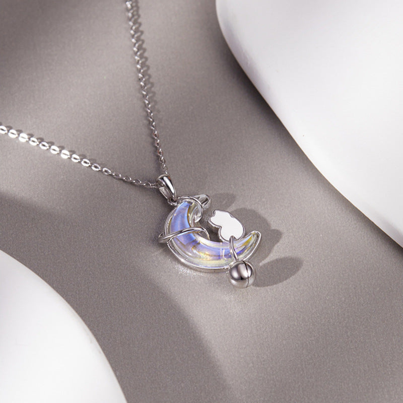 Cat moon necklace showing pale iridescent glass on a gray surface