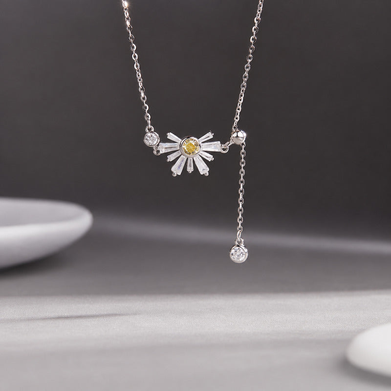 Daisy silver tassel necklace suspended against a gray background