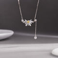 Daisy silver tassel necklace suspended against a gray background