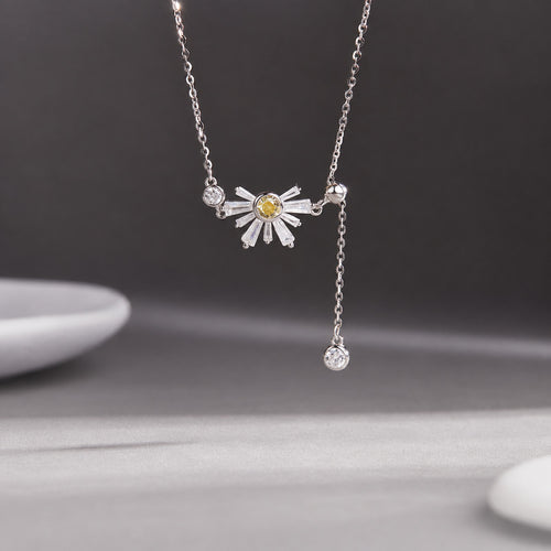 Daisy silver tassel necklace suspended against a gray background