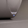 Purple enamel butterfly necklace against its original gray background