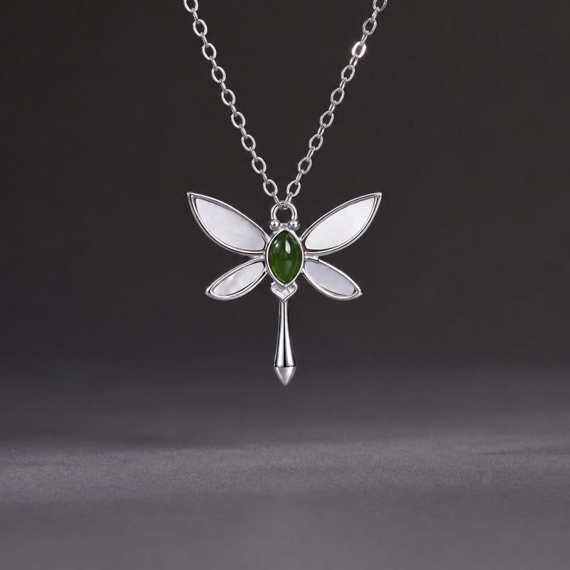 Nephrite jade and white mother-of-pearl dragonfly necklace on a clean dark gray background