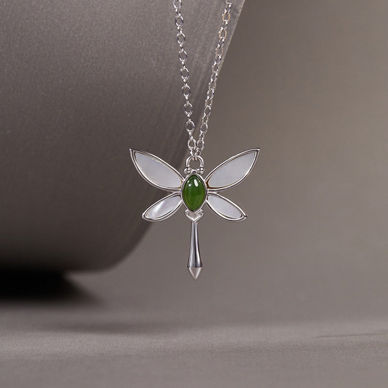 Dragonfly pendant suspended against a gray studio background