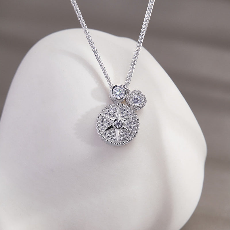 Star compass silver necklace resting on a white sculptural background