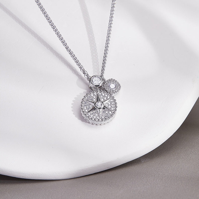 Star compass pendant and chain on a white curved surface
