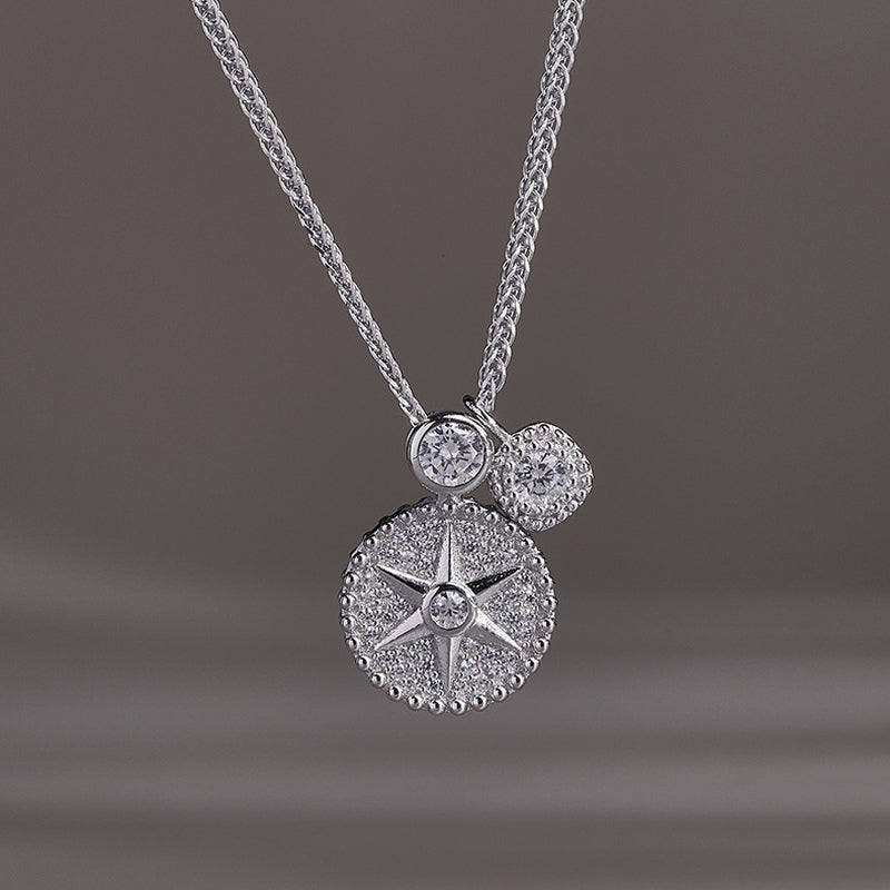 Front view of the silver star compass pendant on a gray background