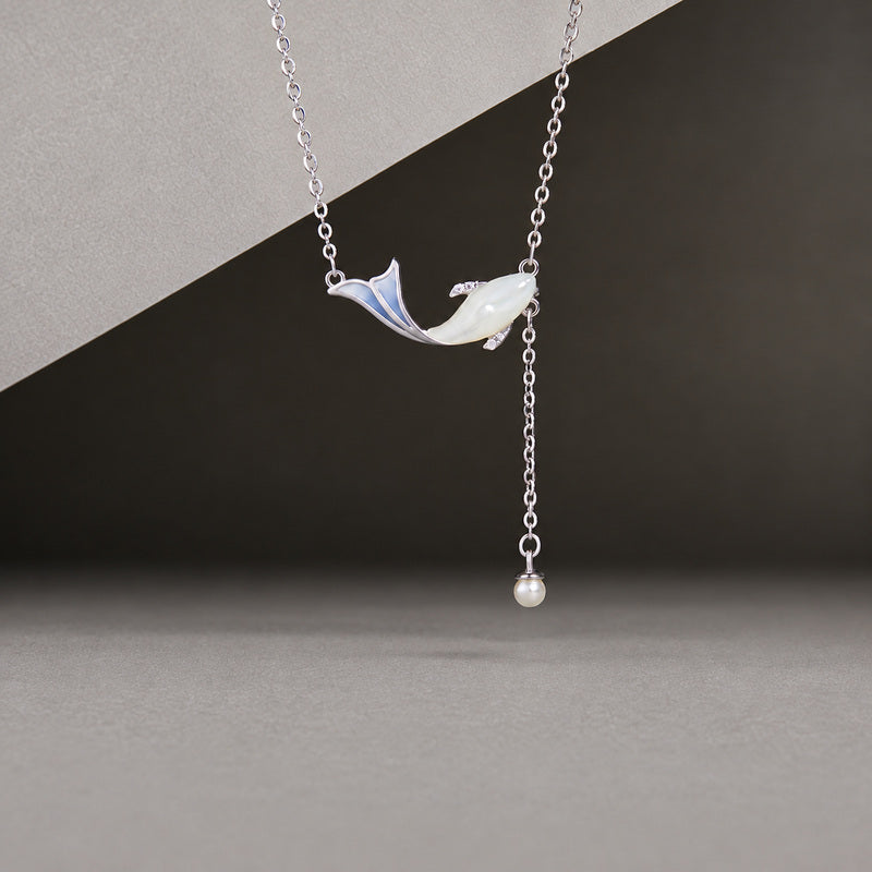 Mother-of-pearl whale necklace with blue enamel tail and synthetic pearl drop on a gray background