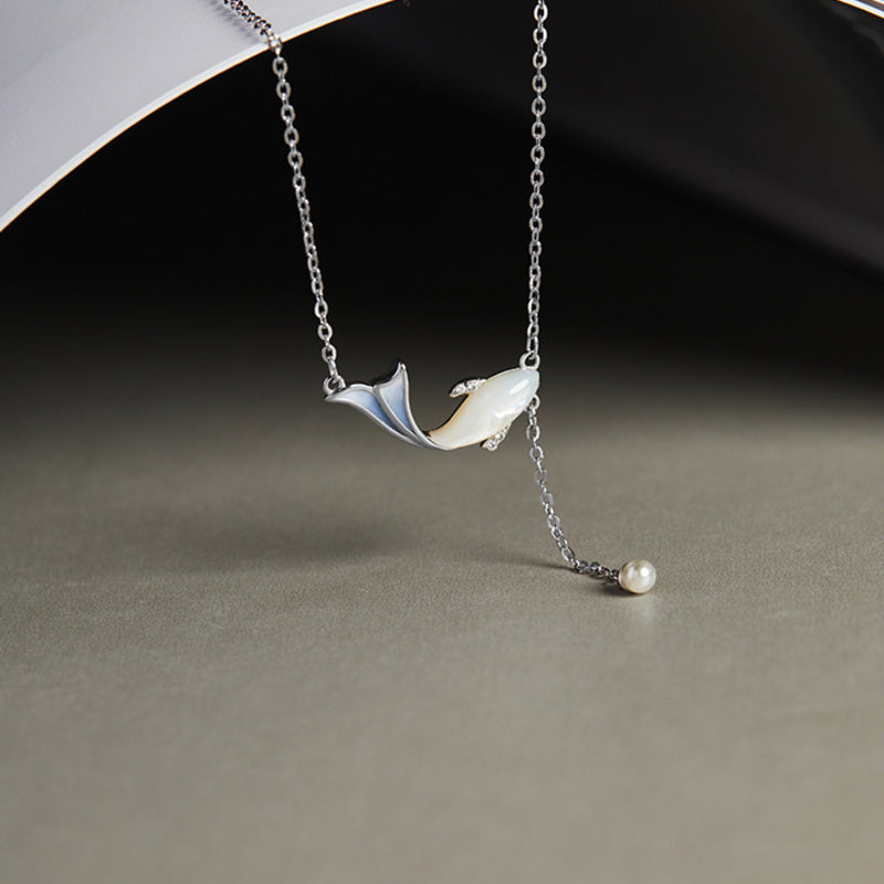 Whale necklace suspended over a curved prop