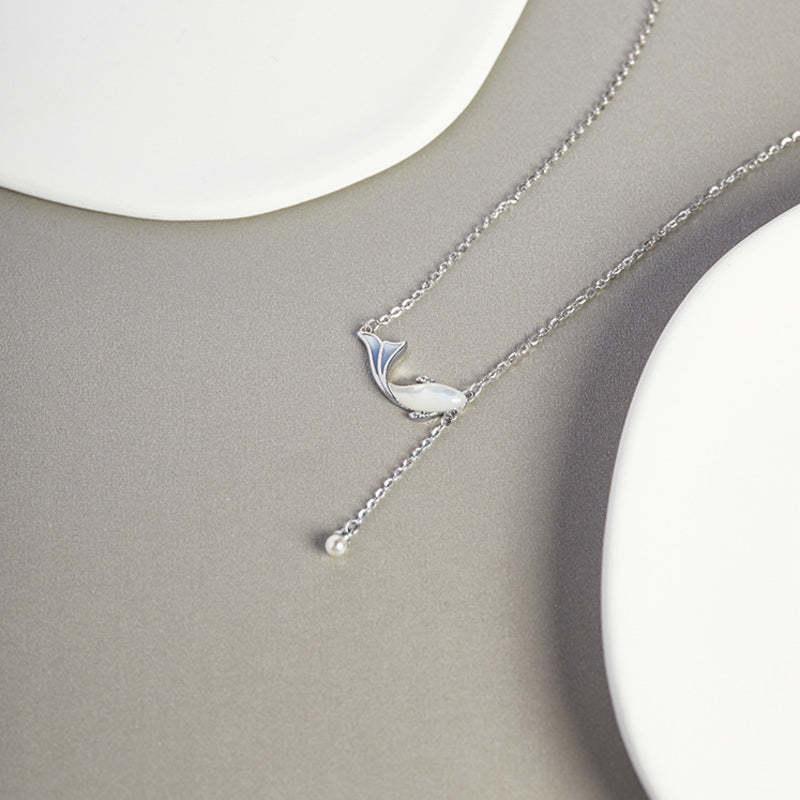 Whale necklace laid on a gray surface