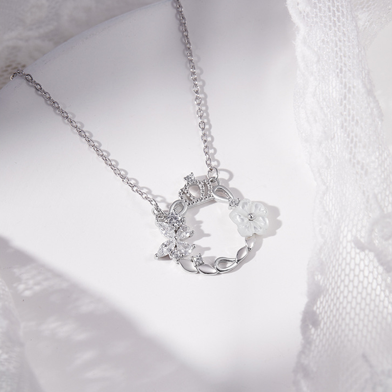 Crown butterfly and white shell flower necklace on a white plate