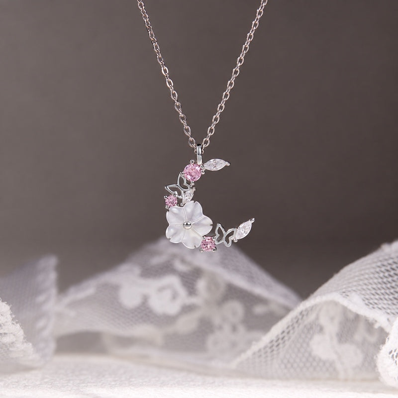 Moon and blossom necklace suspended against gray and white lace