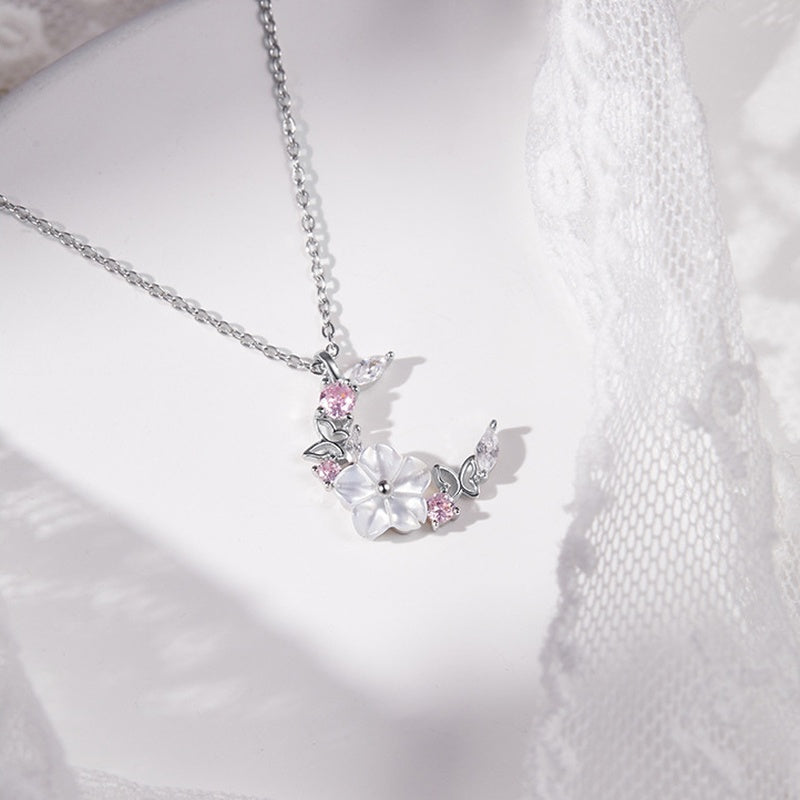 Moon and blossom pendant beside white lace