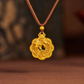 Gold-tone orchid filigree pendant on its original warm background