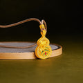 Lotus gourd pendant with green enamel resting against a round display