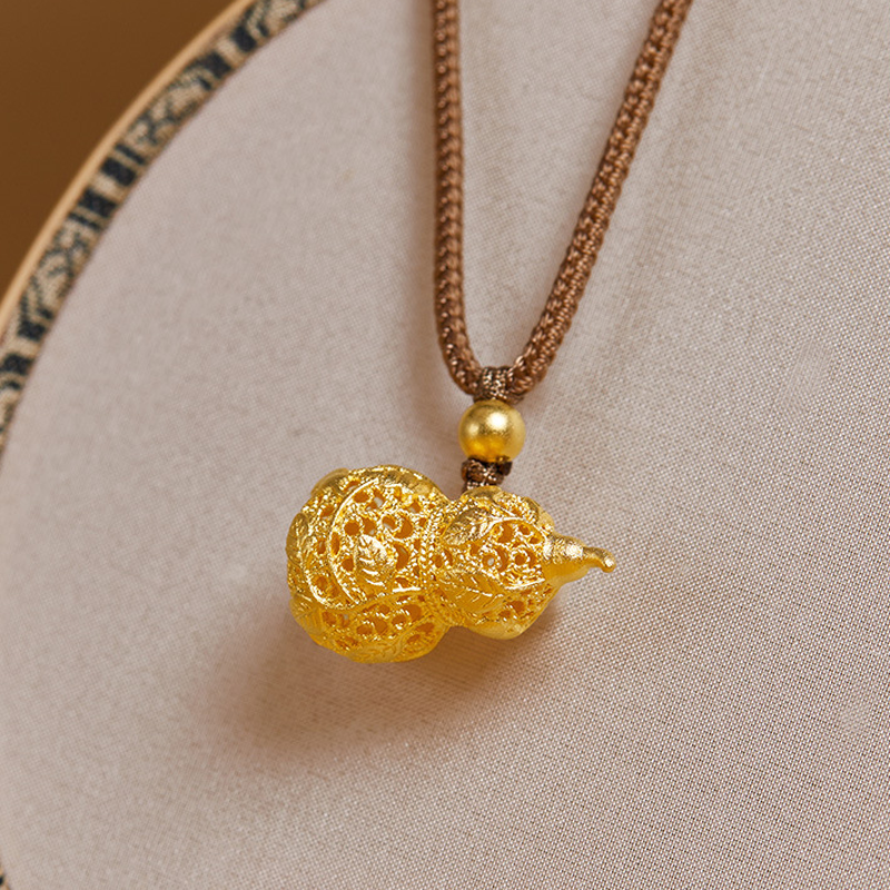 Filigree vine gourd necklace resting on a cream tray