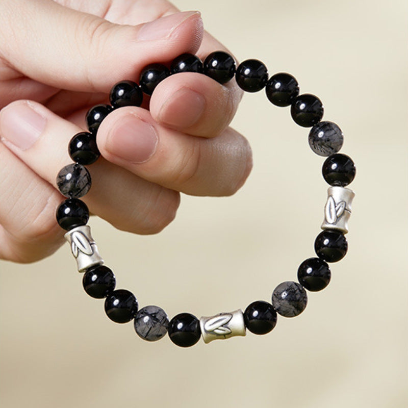 Hand holding bamboo black obsidian and black rutilated quartz bracelet