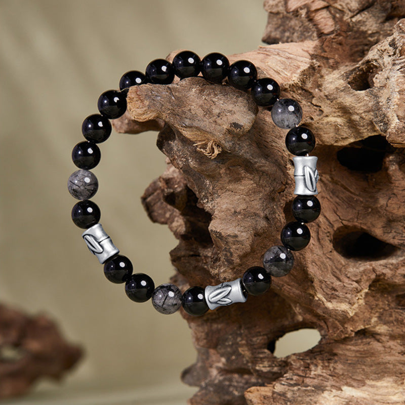 Bamboo black obsidian bracelet displayed on natural wood