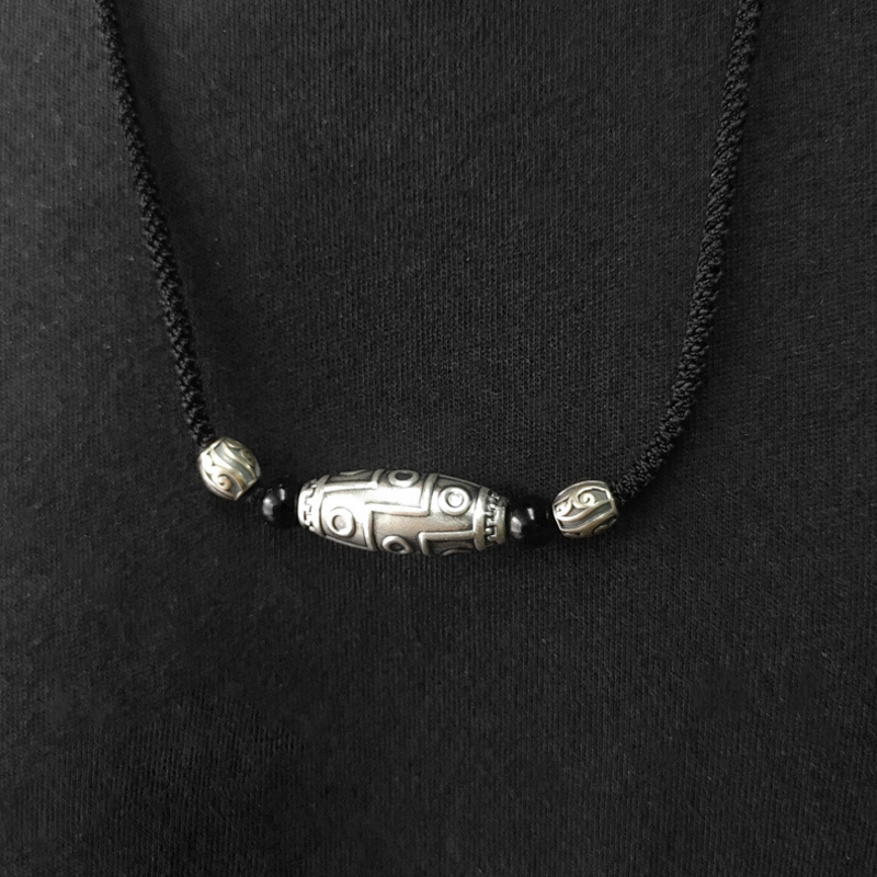 Original model wearing the nine-eye Dzi necklace against a black top