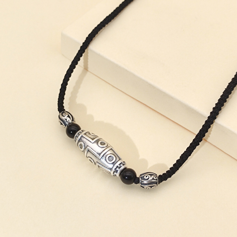 Angled view of the silver Dzi pendant and obsidian beads