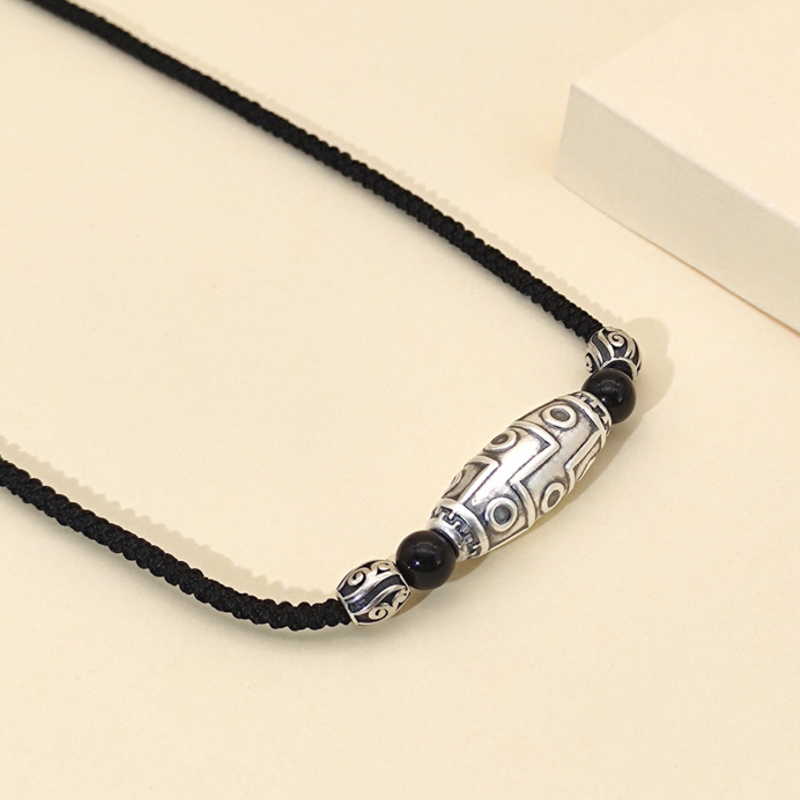 Eye-pattern silver cylinder and braided cord on cream background